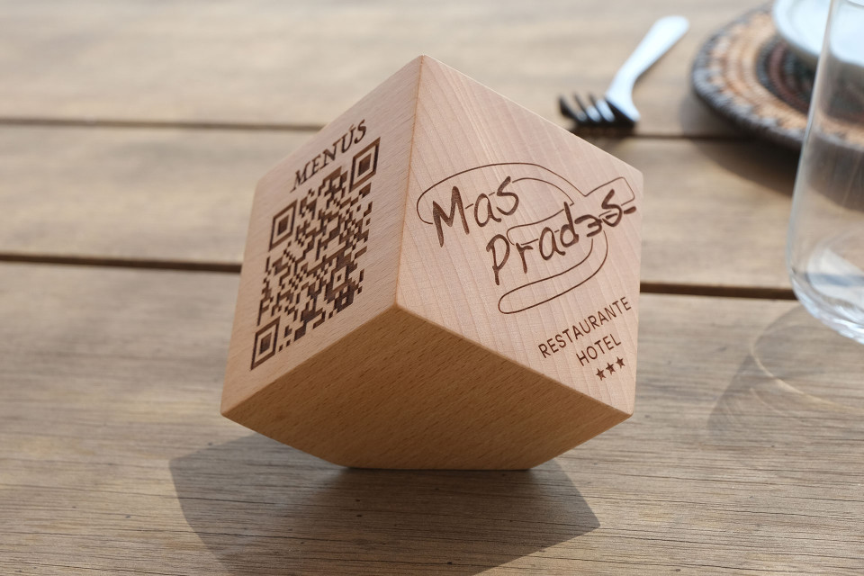Cubo QR de madera con grabado láser sobre una mesa de restaurante